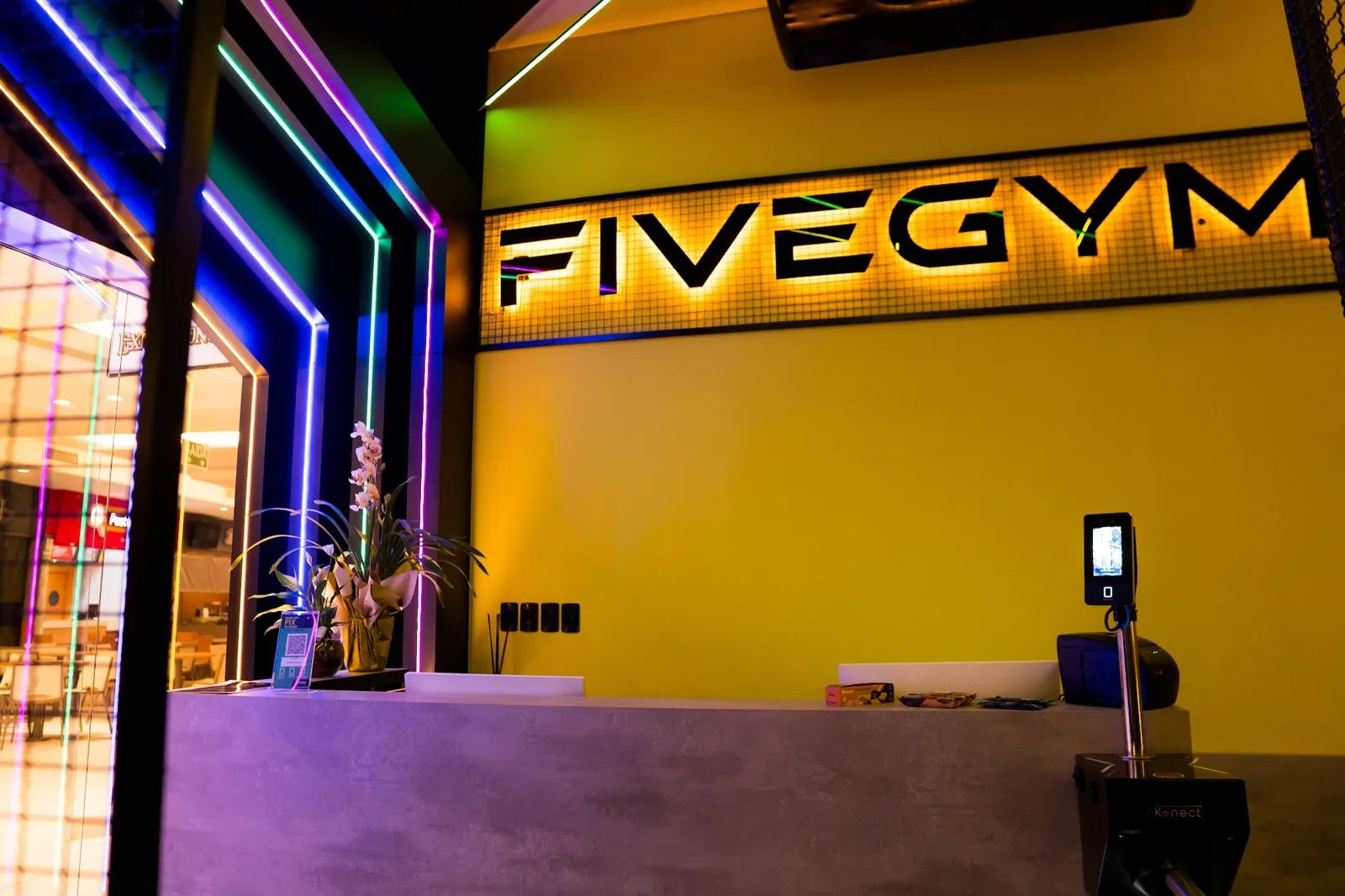 Recepção amarela da Five Gym com o letreiro iluminado